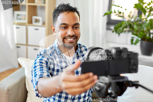 Image of indian male video blogger adjusting camera at home