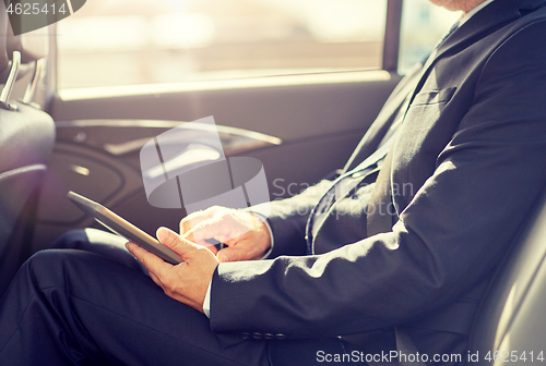 Image of senior businessman with tablet pc driving in car