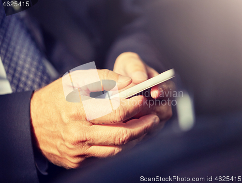 Image of senior businessman texting on smartphone in car