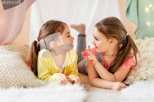 Image of happy girls lying in kids tent and talking at home