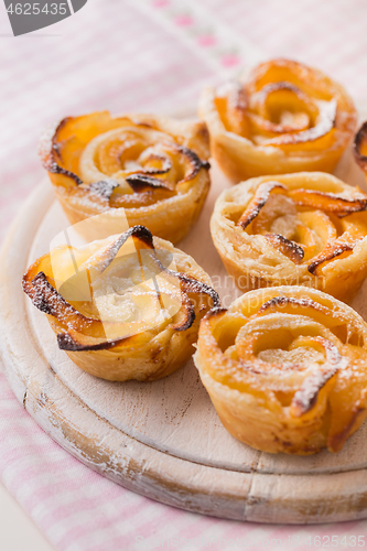 Image of Delicious apple puff pastry in rose shape on wooden board