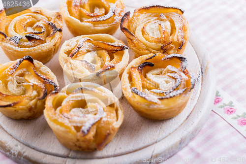 Image of Delicious apple puff pastry in rose shape on wooden board