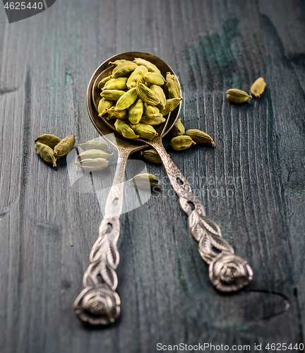 Image of Green cardamom whole seeds in vintage spoon