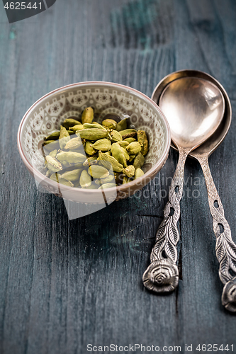 Image of Green cardamom whole seeds in vintage bowl