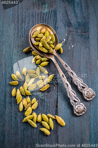 Image of Green cardamom whole seeds in vintage spoon