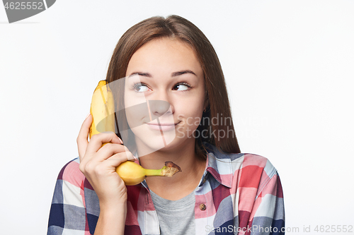 Image of Teen girl holding banana like a phone, looking to side