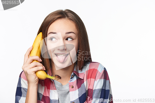 Image of Teen girl holding banana like a phone, looking to side