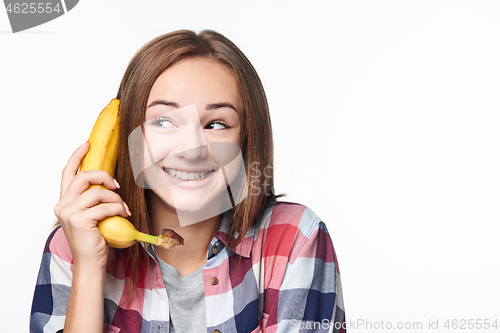 Image of Happy emotional teen girl holding banana like a phone