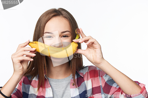 Image of Teen girl holding banana like a smile in front of her lips