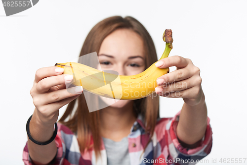 Image of Teen girl outstretching giving you a banana, forming a creative smile in front of her face