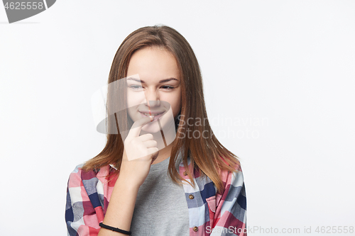 Image of Sly teen girl thinking biting her finger looking to side