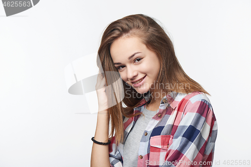 Image of Smiling teen girl touching her hair looking at camera