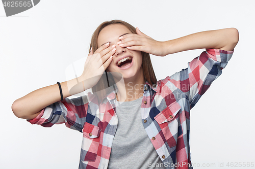 Image of Emotional joyful teen girl covering her eyes with palms