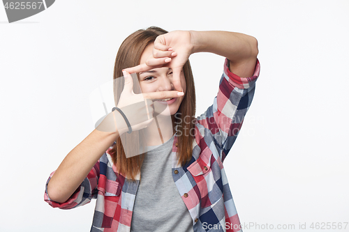 Image of Smiling teen girl looking at camera through finger frame