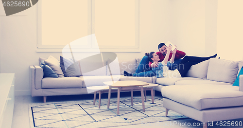 Image of couple relaxing at  home with tablet computers