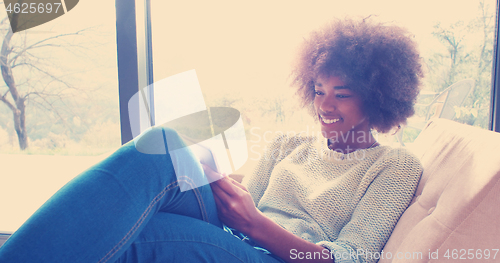 Image of african american woman at home using digital tablet