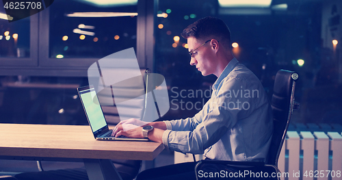 Image of man working on laptop in dark office