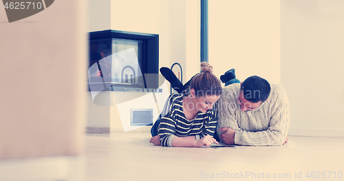 Image of Young Couple using digital tablet on the floor