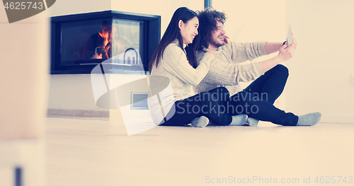 Image of Young Couple using digital tablet on the floor