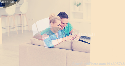 Image of couple relaxing at  home with tablet computers