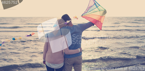 Image of Happy couple having fun with kite on beach