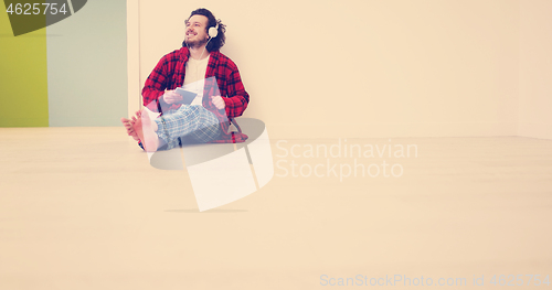 Image of young man listenig music on tablet at home