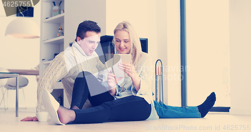 Image of Young Couple using digital tablet on the floor