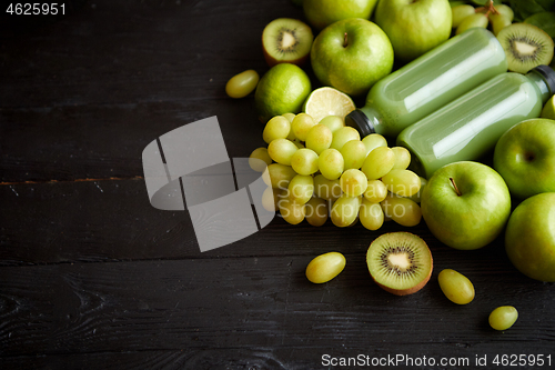 Image of Mixed green fruits and vegetables placed on black wooden table