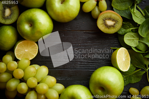 Image of Mixed green fruits and vegetables placed on black wooden table