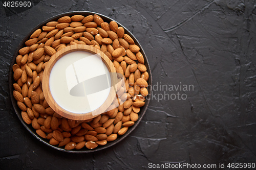 Image of Composition of almonds seeds and milk, placed on black stone background.