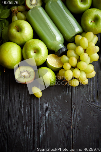 Image of Mixed green fruits and vegetables placed on black wooden table