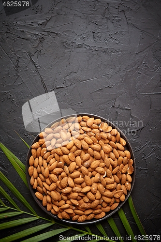 Image of Composition of Whole almond nuts in black plate placed on black stone table