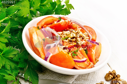 Image of Salad with tomato and walnut in plate on light wooden board