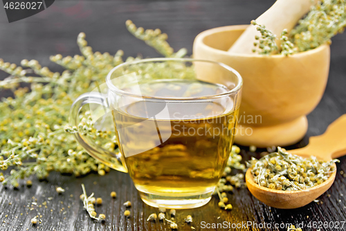 Image of Tea of gray wormwood in glass cup with mortar on dark board