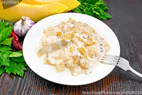 Image of Pumpkin with sour cream sauce in plate on dark board