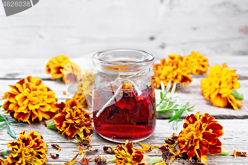 Image of Alcohol tincture of marigolds in jar on old board