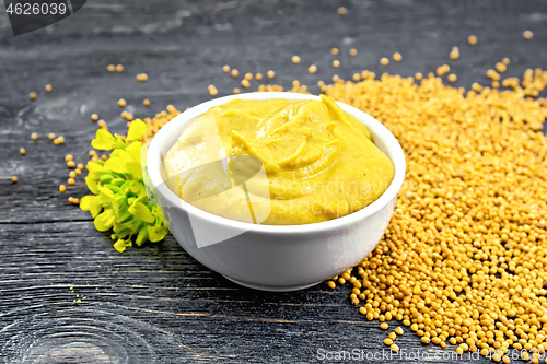 Image of Sauce mustard in bowl with seeds and flower on black board