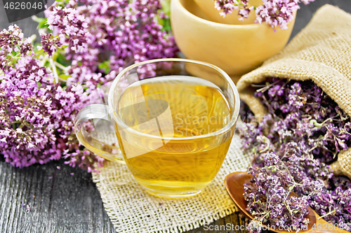 Image of Tea of oregano in cup with mortar on wooden board