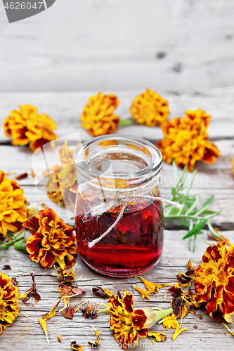 Image of Alcohol tincture of marigolds in jar on old wooden board