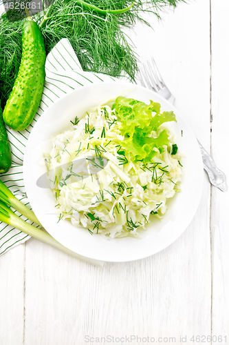 Image of Salad of cabbage with cucumber in plate on light board top