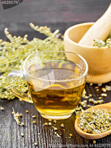 Image of Tea of gray wormwood in glass cup with mortar on wooden board