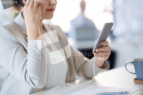 Image of businesswoman with earphones and smartphone