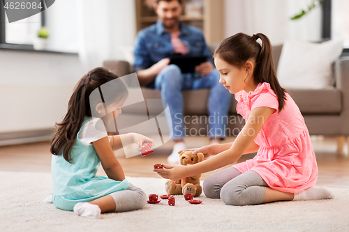Image of girls playing with toy crockery and teddy at home