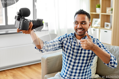 Image of male video blogger with camera blogging at home