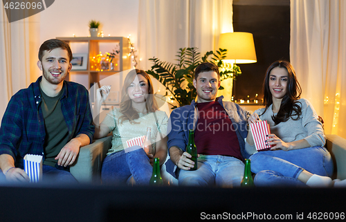 Image of friends with beer and popcorn watching tv at home