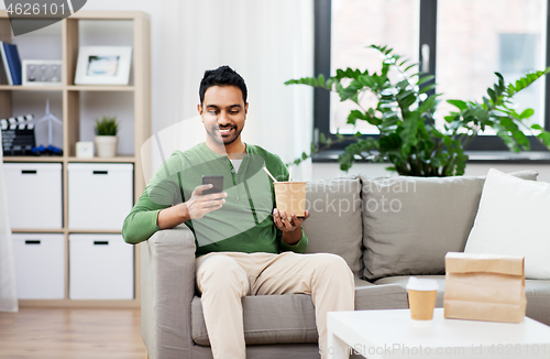 Image of smiling indian man eating takeaway food at home