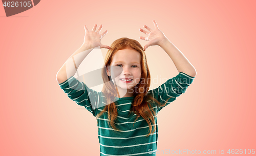 Image of red haired girl having fun and making big ears