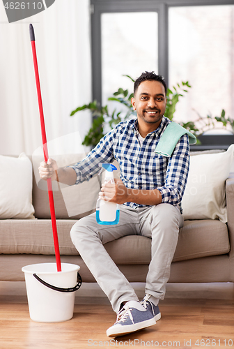 Image of indian man with mop and detergent cleaning at home