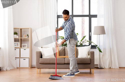 Image of man with broom cleaning floor at home