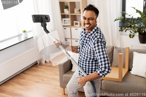 Image of man in headphones with vacuum cleaner at home